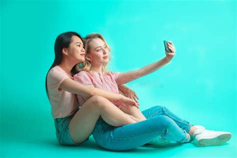 Portrait Of A Two Joyful Females Taking A Selfie While Sitting On Floor