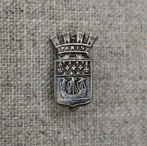 A Silver Pin With An Image Of Paris On It S Front And Back Side