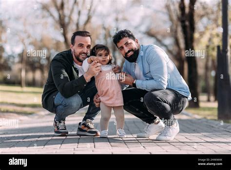 Portrait Of A Male Gay Couple Enjoying With Their Daughter In The Park Adoption Concept Stock