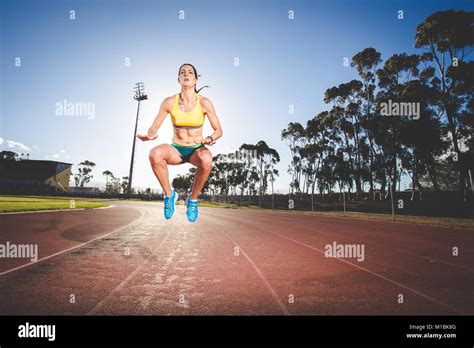 Female fitness model and track athlete sprinting on an athletics track ...