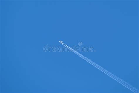 Distant Passenger Jet Plane Flying On High Altitude On Clear Blue Sky