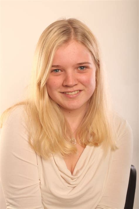 A Woman With Blonde Hair Sitting In A Chair Smiling At The Camera While