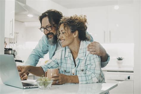 Happy Husband And Wife Enjoying Time In The Kitchen Using Laptop