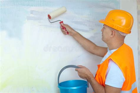 Painter Man At Work With A Paint Roller Wall Painting Stock Photo