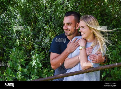 Smiling Man Hugging Blonde Girlfriend Behind Gate Stock Photo Alamy