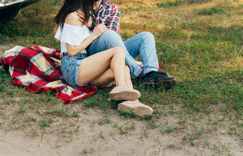 Loving Couple Sits On A Red Plaid In The Woods And Embrace The Couple