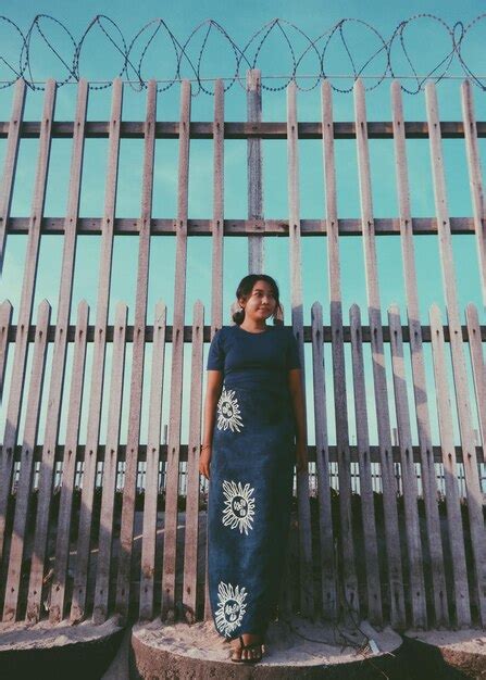 Premium Photo Young Woman Standing Against Fence