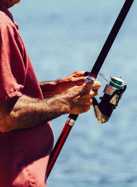 Pescador As M Os Segurando Uma Vara De Pescar De Perto Foto Premium