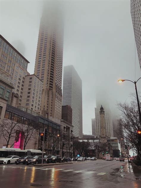 An Empty City Street With Tall Buildings In The Background On A Foggy