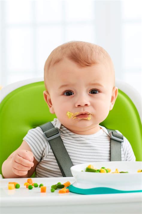 A Baby Sitting In A High Chair Eating Food