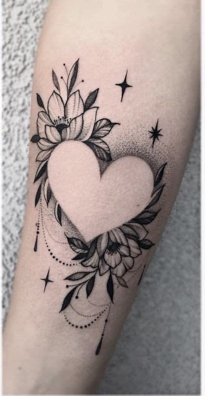 A Black And White Heart Tattoo With Flowers On The Side Of Her Arm