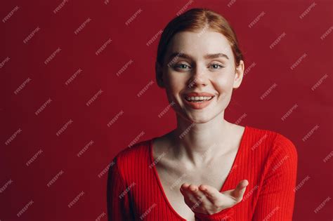 Premium Photo Portrait Of Beautiful Young Redhaired Woman Blowing Kisses Over Red Background