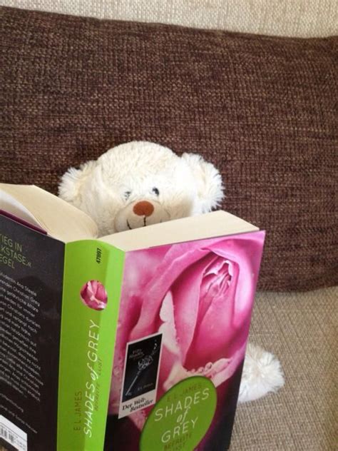 A White Teddy Bear Sitting On Top Of A Couch Next To An Open Book With