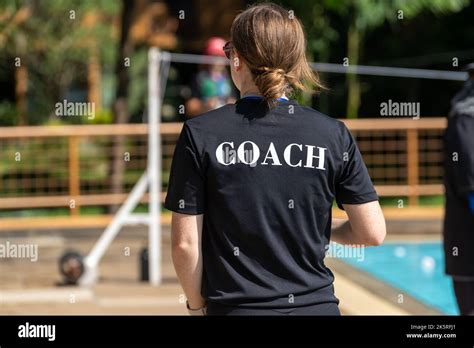 Back View Of Swimming Coaches Wearing Coach Shirt Working At An