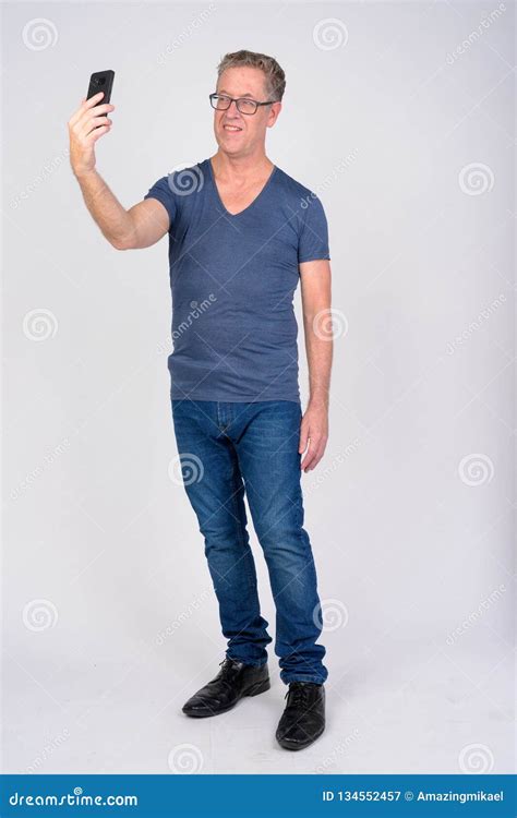 Full Body Shot Of Happy Mature Man Taking Selfie Against White