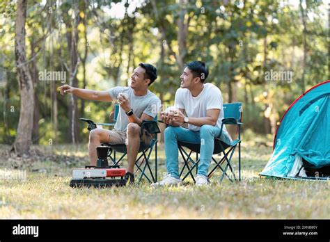 Couple Lgbt Gay Enjoying A Relaxing Morning Camping Outdoors With Coffee Near Tent Stock Photo