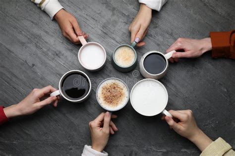 People Holding Different Cups With Aromatic Hot Coffee At Grey Table