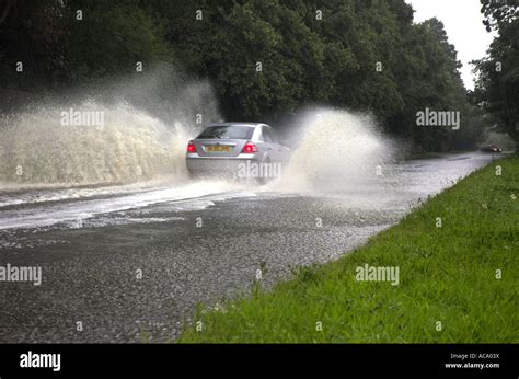 Car Driving Through Flooded Road Spraying Water After Heavy Rain Stock