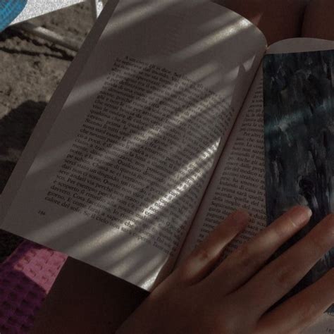 A Person Is Reading A Book On The Ground With Their Hands Resting On An