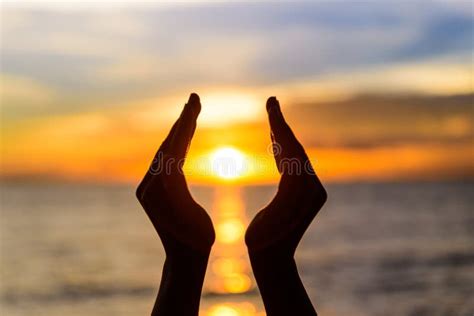 Woman Hands Holding The Sun During Sunrise Or Sunset Stock Photo