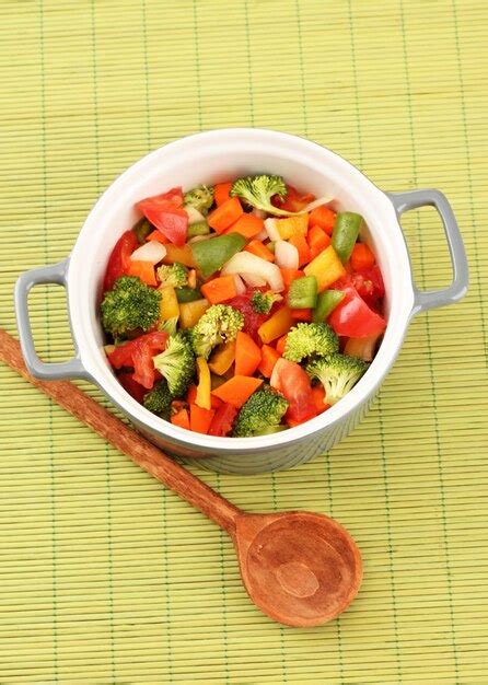 Estofado de verduras en una olla gris sobre fondo de estera de bambú