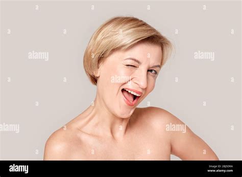 Beauty Conept Mature Blonde Woman Standing Isolated On Grey Winking To