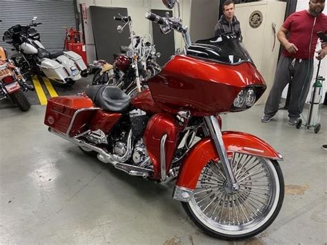 A Red Motorcycle Parked Inside Of A Garage Next To Other Motorcycles