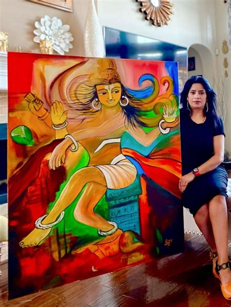 a woman sitting in front of two paintings on the floor next to a table ...