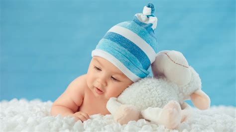 Beautiful Cute Baby Is Lying Down On White Cloth Wearing Blue And White