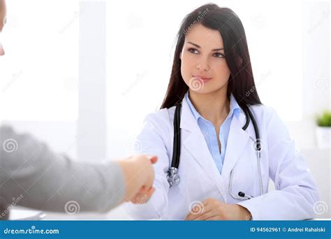 Brunette Female Doctor Shaking Hands With Patient During A Conversation