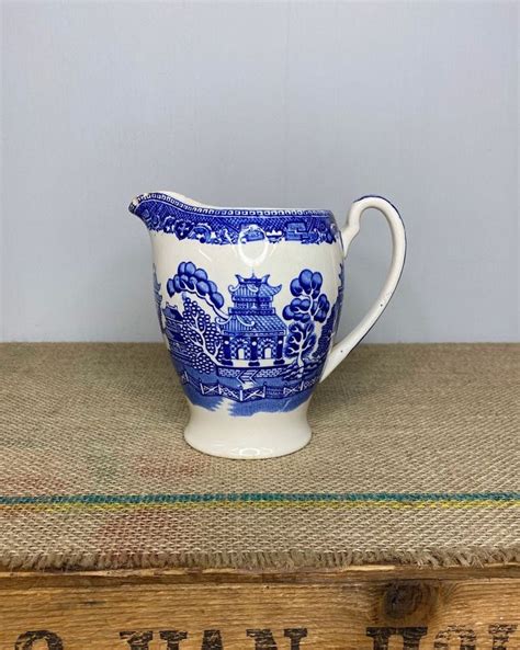 A Blue And White Porcelain Pitcher Sitting On Top Of A Wooden Box Next