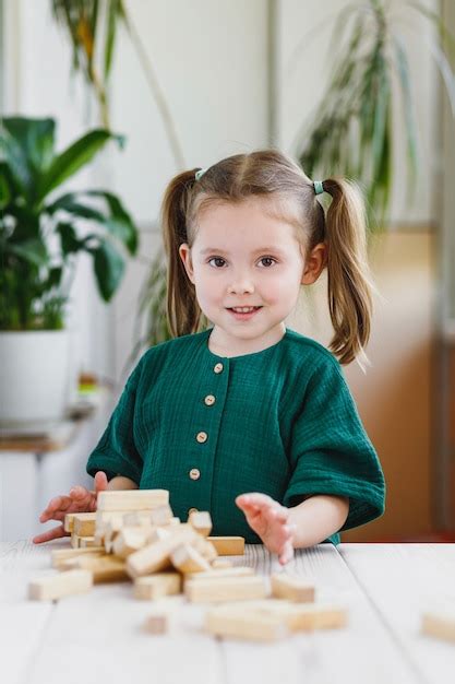 Souriant Enfant Mignon Et Astucieux En Robe Verte Et Tour De Jenga En