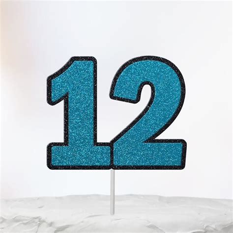 A Blue Number Twelve Cake Topper Sitting On Top Of A White Cake