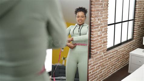 African American Woman Measuring Abdomen With Tape Measure Looking On