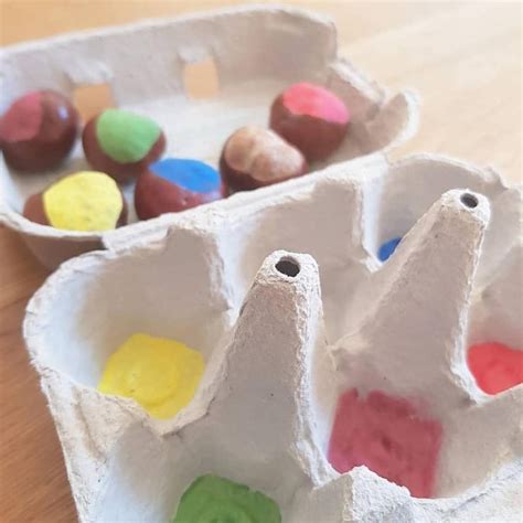 An Egg Carton Filled With Different Colored Eggs On Top Of A Wooden Table