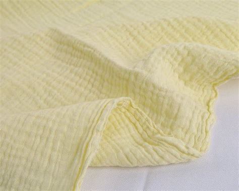 An Unmade Bed With White Sheets And Yellow Blankets