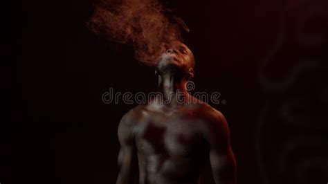 Black Guy With Naked Torso Smokes It Emits Smoke From Which Various Figures Are Formed Stock