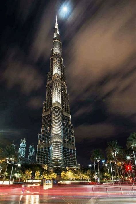 The Burj Building Is Lit Up At Night With Bright Lights And Clouds In