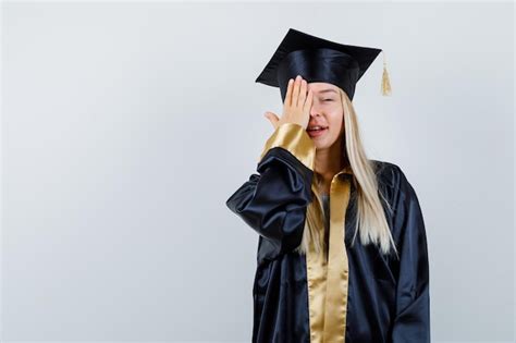 학술 드레스에 손으로 눈을 덮고 귀여운 찾고 젊은 아가씨 무료 사진