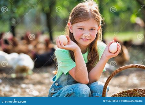 Young Girl Holding Chicken Eggs From A Wicker Basket On A Farm With