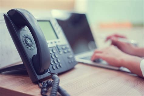 Close Up Handset Telephone Voip With Employee Man Working On Laptop