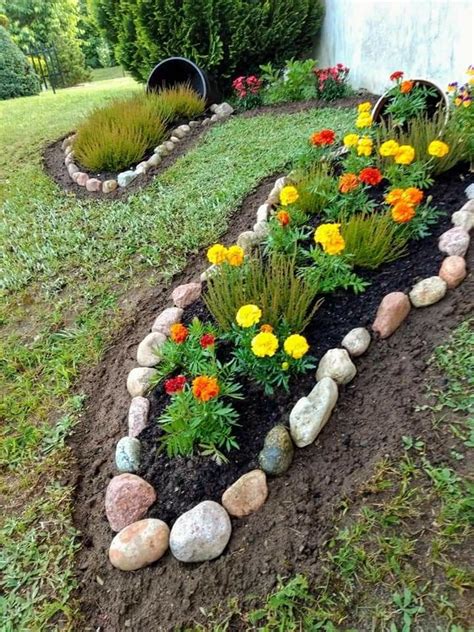 A Garden With Flowers And Rocks In The Middle Of It Along Side A House