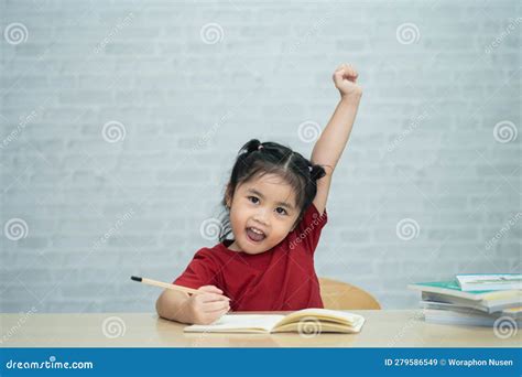 Asian Baby Girl Wearing A Red Shirt Write Notes In Notebook And Reading