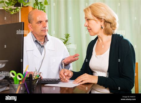Male Doctor Talking With Mature Patient In Clinic Office Stock Photo