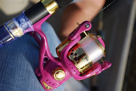 A Person Holding A Pink Fishing Reel In Their Hand