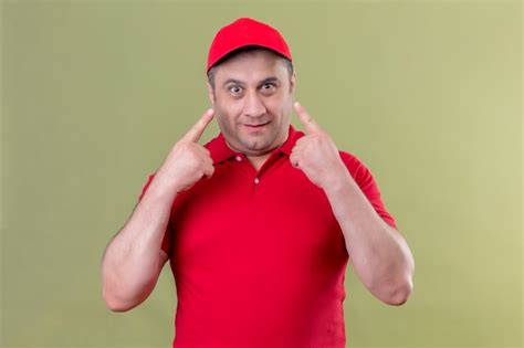 Free Photo Delivery Man In Red Uniform And Cap Smiling Pointing His