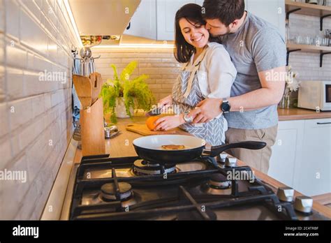 Lovely Couple Hugging On The Kitchen While Cooking Breakfast Stock