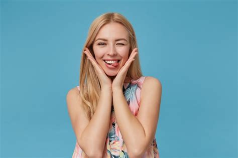 Drôle De Jeune Femme Blonde Clignant Des Yeux Et Montrant La Langue Joyeusement Debout En Robe