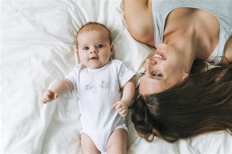 Jovem mãe se divertindo uma linda garotinha na cama tons