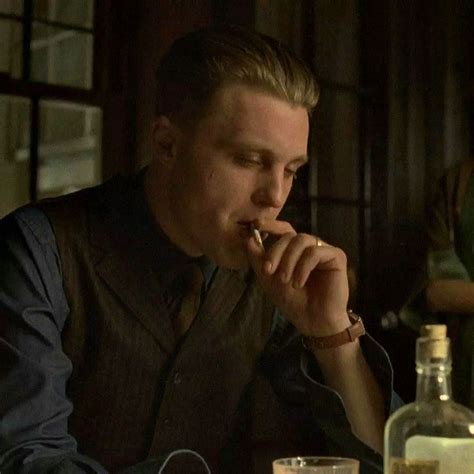 A Man Sitting At A Table With A Glass In Front Of Him Eating Something